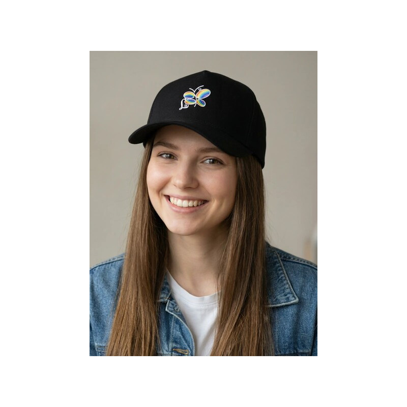 Joven vistiendo gorra negra con logo de libélula arcoíris de la marca lisviv