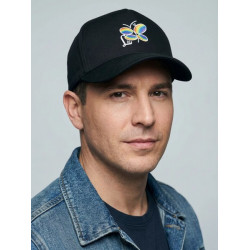 Modelo mostrando gorra negra de la marca lisviv, destacando logo de libélula multicolor