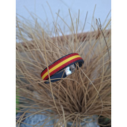 Pulsera de piel autentica con bandera de España colocada sobre un jarrón de esparto.