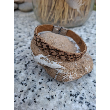 Pulsera de piel marrón con grabado efecto trenzado sobre una piedra.