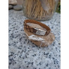 Detalle de cierre de acero inoxidable en pulsera de piel marrón.