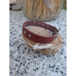 Grabado de logotipo lisviv artesanal en pulsera de piel granate sobre piedra.