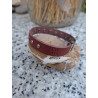Grabado de logotipo lisviv artesanal en pulsera de piel granate sobre piedra.