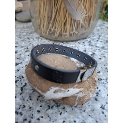 Logotipo lisviv grabado en pulsera de piel negra colocada sobre piedra.