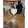 Detalle de la figura de corazón de cemento fosforescente de día junto a frascos de perfume