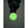 Efecto de iluminación verde fosforescente de la flor de caléndula colgada en un aplique a oscuras.