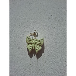 Adorno colgante de mariposa en cemento blanco de día fijado en una pared blanca exterior.