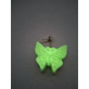Efecto de brillo verde fosforescente de la mariposa decorativa colgada en la pared a oscuras.