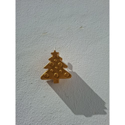 Adorno navideño de árbol de cemento pintado en color oro colgado de una pared con luz de sol.