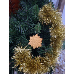 Adorno navideño con silueta de estrella copo de nieve en cemento color oro colgada en las ramas del abeto.