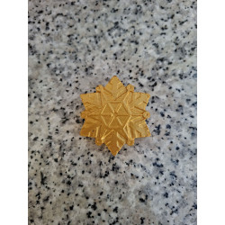 Primer plano del relieve geométrico de la estrella copo de nieve de cemento en color oro.