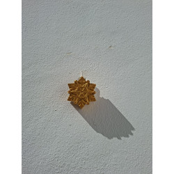 Silueta de estrella navideña en cemento pintada de color oro colgada en la pared con cordón rústico.