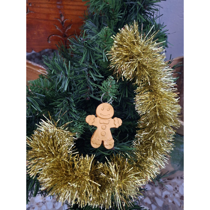 Adorno navideño con silueta de muñeco de jengibre en cemento color oro colgado en el abeto festivo.