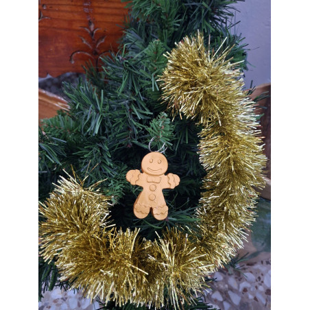 Adorno navideño con silueta de muñeco de jengibre en cemento color oro colgado en el abeto festivo.