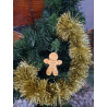 Adorno navideño con silueta de muñeco de jengibre en cemento color oro colgado en el abeto festivo.