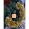 Adorno navideño con silueta de paquete de regalo en cemento color oro colgado en el árbol de Navidad.