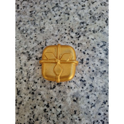 Detalle en primer plano del relieve del lazo y la cinta en la figura de regalo de Navidad de cemento color oro.