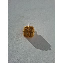 Adorno navideño con forma de caja de regalo en cemento pintado de oro colgado en la pared de día.