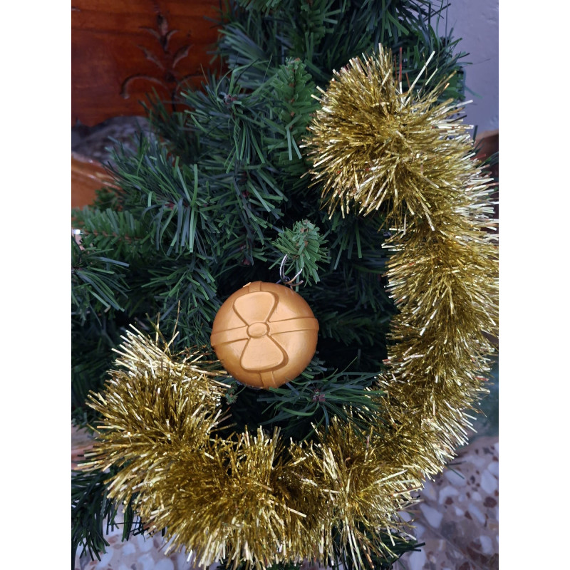 Adorno navideño de bola redonda de cemento pintada en color oro con relieve de cintas y lazo colgada en abeto.