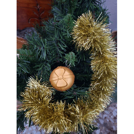 Adorno navideño de bola redonda de cemento pintada en color oro con relieve de cintas y lazo colgada en abeto.