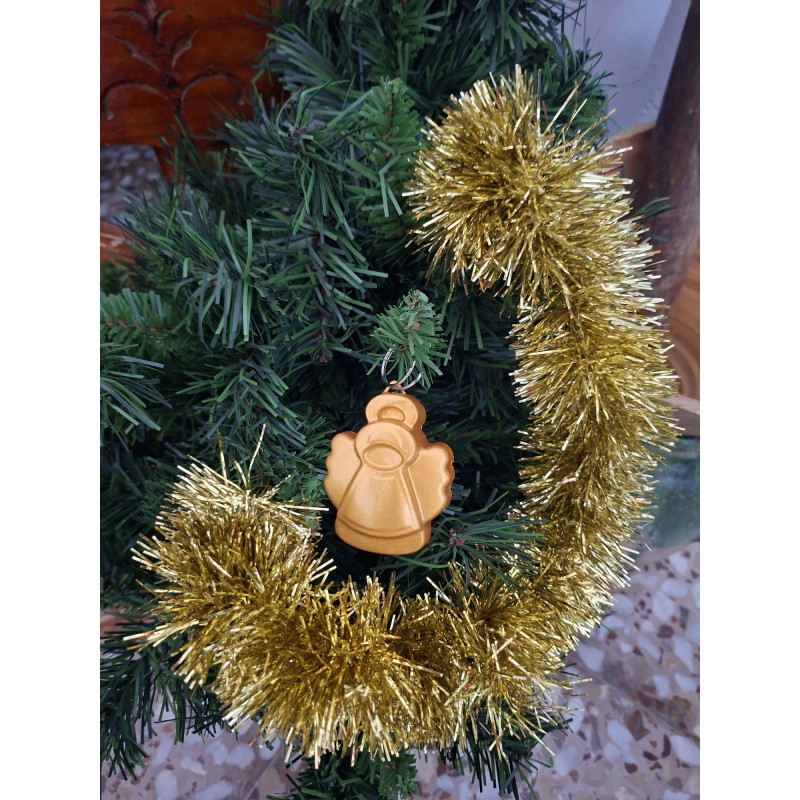 Adorno navideño con silueta de ángel celestial en cemento color oro colgado en el árbol de Navidad.