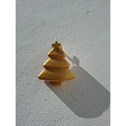 Adorno navideño con silueta de árbol liso minimalista en cemento pintado de oro colgado en la pared de día.