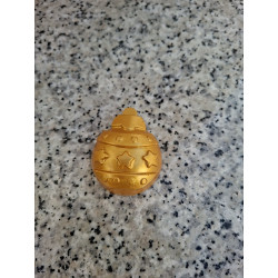 Detalle en primer plano de la cenefa de estrellas y líneas de puntos grabadas en la bola de Navidad de cemento oro.