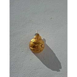 Esfera navideña de cemento oro con relieves de cenefa de estrellas y puntos colgada en la pared de día.