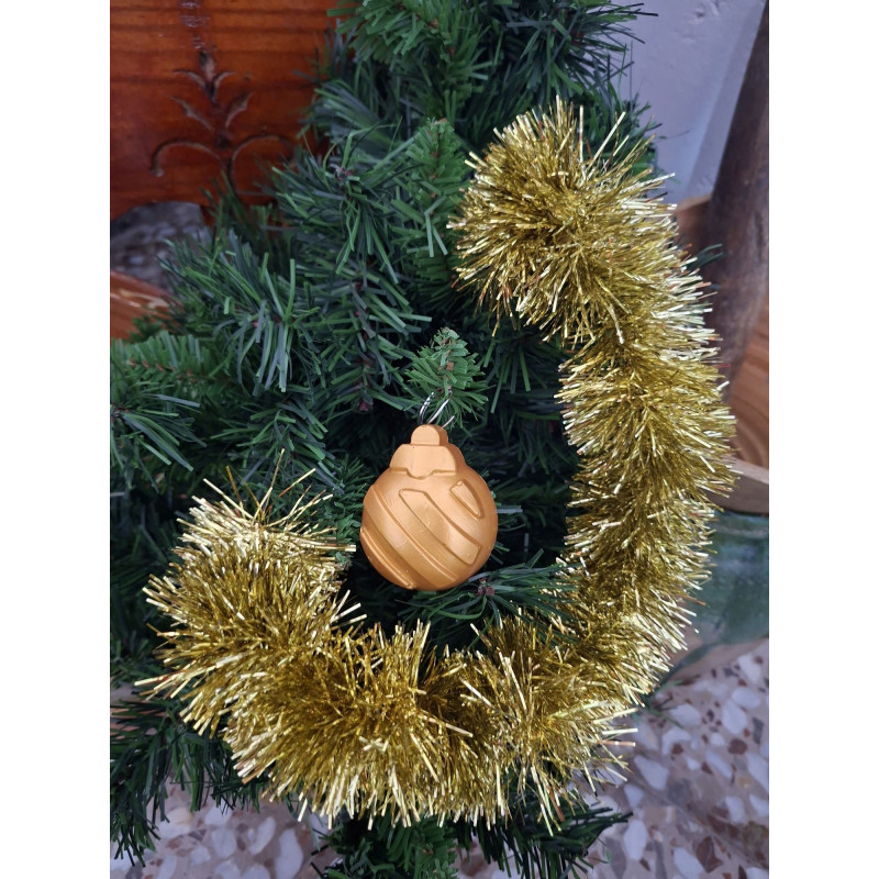 Adorno navideño de bola de cemento pintada en color oro con relieve de líneas diagonales oblicuas colgada en abeto.