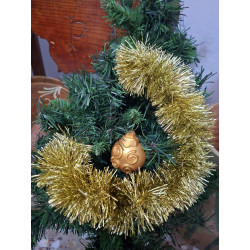 Adorno navideño de bola de cemento pintada en color oro con relieve de líneas en espiral y volutas colgada en abeto.