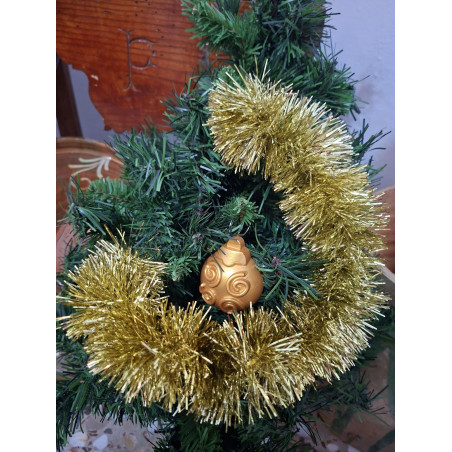 Adorno navideño de bola de cemento pintada en color oro con relieve de líneas en espiral y volutas colgada en abeto.