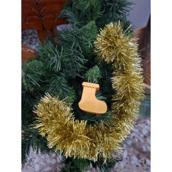 Adorno navideño con silueta de calcetín de cemento pintado en color oro colgado en el abeto festivo.