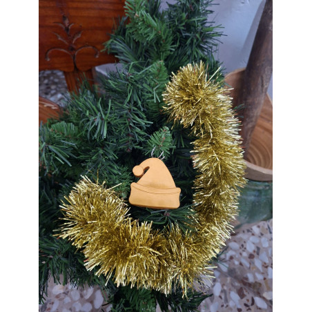 Adorno navideño con silueta de gorro de Papa Noel en cemento color oro colgado en el abeto festivo.