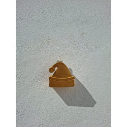 Gorro navideño de cemento pintado en color oro colgado en la pared con cordón rústico de día.