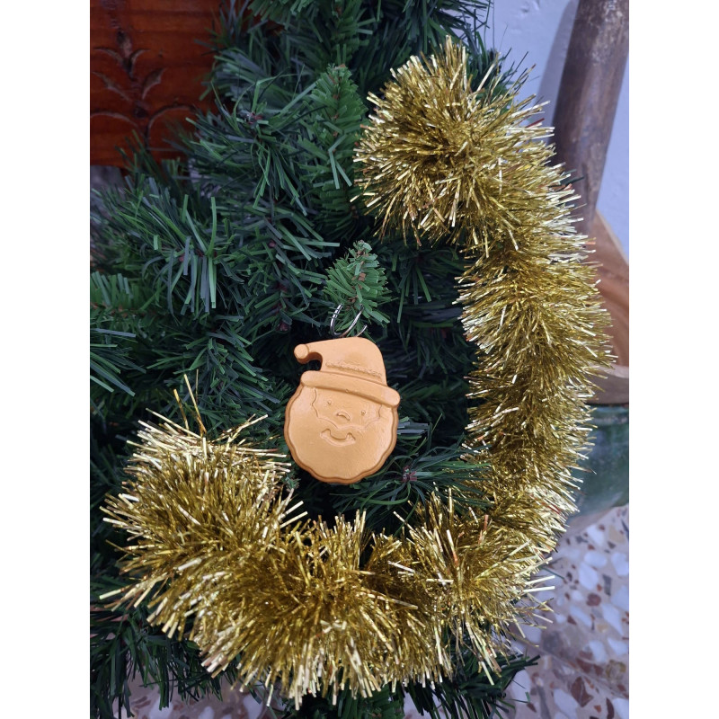 Adorno navideño con silueta del rostro de Papa Noel en cemento color oro colgado en el árbol de Navidad.