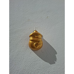 Figura de Papá Noel asomando en chimenea de cemento pintada de oro colgada en la pared de día.