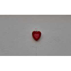 Adorno de corazón de cemento pintado a mano con relieve doble colgado en una pared texturizada blanca.