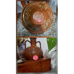 Adorno de flor de cemento pintado a mano color rosa colocado en lebrillo tradicional de barro y junto a vasija rústica.