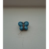 Adorno de mariposa de cemento azul intenso pintado a mano colgado verticalmente en una pared blanca exterior.