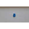Adorno de osito pequeño de cemento azul intenso pintado a mano colgado de manera vertical en una pared blanca exterior.