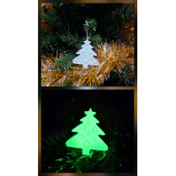 Adorno de árbol de navidad de cemento fosforescente colgado en el abeto y mostrando su brillo verde en la oscuridad.