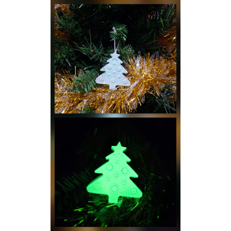 Adorno de árbol de navidad de cemento fosforescente colgado en el abeto y mostrando su brillo verde en la oscuridad.