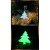 Adorno de árbol de navidad de cemento fosforescente colgado en el abeto y mostrando su brillo verde en la oscuridad.