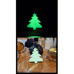 Adorno de árbol de navidad de cemento fosforescente mostrando su brillo verde y su diseño en un tocador de mármol.