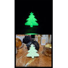Adorno de árbol de navidad de cemento fosforescente mostrando su brillo verde y su diseño en un tocador de mármol.