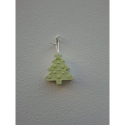 Adorno de árbol de navidad de cemento fosforescente con relieve de bolas colgado de forma vertical en una pared blanca exterior.