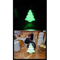 Adorno de árbol de Navidad de cemento fosforescente escalonado mostrando su brillo verde y su silueta de día sobre mármol.