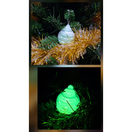 Adorno bola de Navidad de cemento fosforescente con relieve de estrellas de día en el abeto y brillando en color verde de noche.