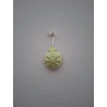 Adorno de bola de Navidad de cemento fosforescente con relieve de copo de nieve colgado de forma vertical en pared exterior.