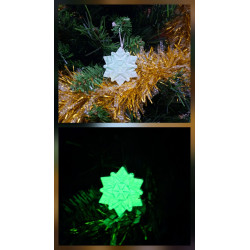 Adorno estrella copo de nieve de cemento fosforescente de día colgado en el abeto y mostrando su brillo verde en la oscuridad.